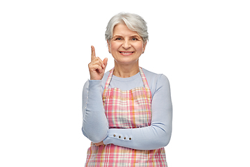 Image showing smiling senior woman in apron pointing finger up