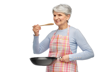 Image showing smiling senior woman in apron with frying pan