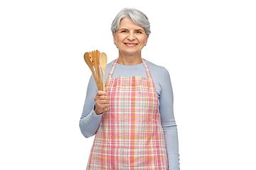 Image showing smiling senior woman in apron with wooden spoons