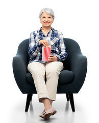 Image showing senior woman eating popcorn sitting in armchair