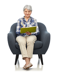 Image showing smiling senior woman in armchair writing to diary