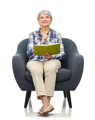 Image showing smiling senior woman in armchair writing to diary