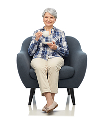 Image showing smiling senior woman drinking coffee in armchair
