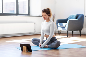 Image showing young woman with tablet pc doing yoga at home