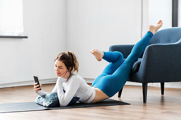 Image showing woman with smartphone stretching yoga at home