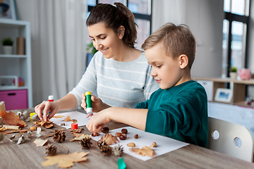 Image showing mother and son making pictures of autumn leaves