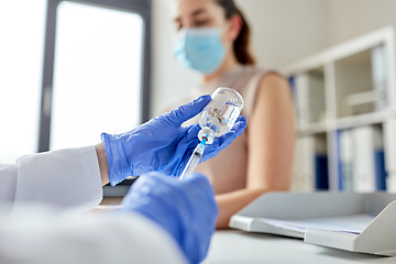 Image showing female doctor with syringe vaccinating patient