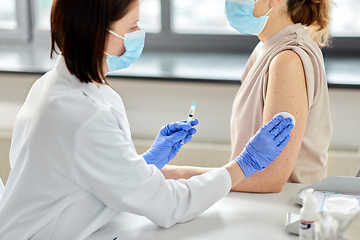 Image showing female doctor with syringe vaccinating patient