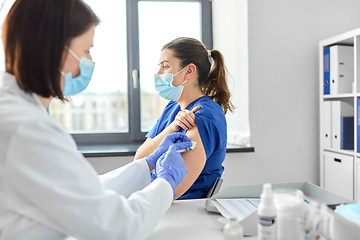 Image showing doctor with syringe vaccinating medical worker