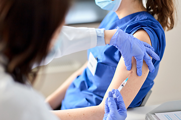 Image showing doctor with syringe vaccinating medical worker