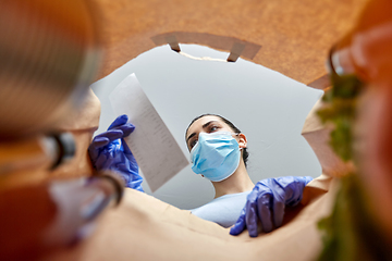 Image showing woman in gloves and mask with bill and food in bag