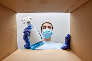 Image showing woman in mask taking cleaning supplies from box