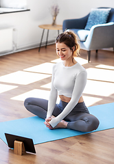 Image showing young woman with tablet pc doing yoga at home