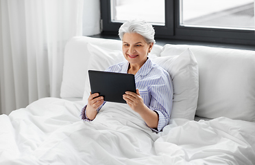 Image showing senior woman with tablet pc in bed at home bedroom