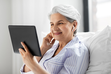 Image showing senior woman with tablet pc and earphones in bed