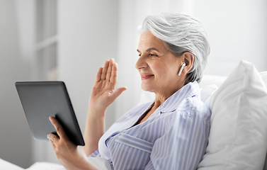 Image showing old woman with tablet pc having video call in bed