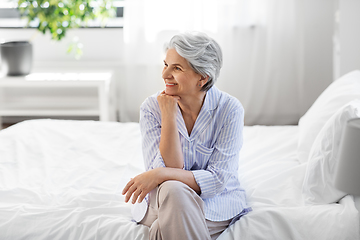 Image showing happy senior woman sitting on bed at home bedroom