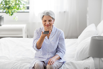 Image showing happy senior woman recording voice on smartphone