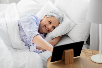 Image showing happy senior woman with tablet pc in bed at home