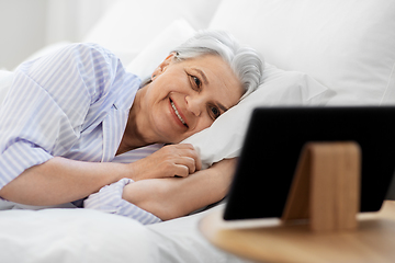 Image showing happy senior woman with tablet pc in bed at home