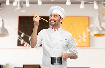 Image showing happy smiling male chef with saucepan tasting food