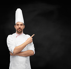 Image showing male chef in toque pointing finger on black