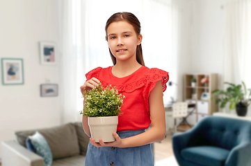 Image showing happy smiling girl holding flower in pot at home