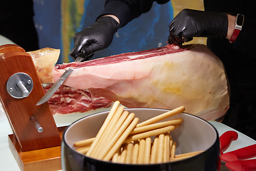 Image showing Sliced dried chamon prosciutto. A man cuts a jamon, a warm toned