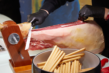 Image showing Sliced dried chamon prosciutto. A man cuts a jamon, a warm toned