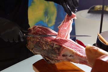 Image showing Sliced dried chamon prosciutto. A man cuts a jamon, a warm toned