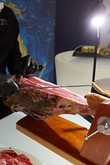 Image showing Sliced dried chamon prosciutto. A man cuts a jamon, a warm toned