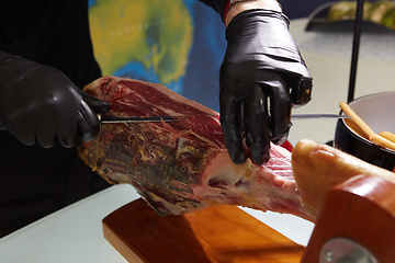 Image showing Sliced dried chamon prosciutto. A man cuts a jamon, a warm toned