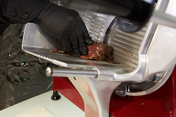 Image showing Man slicing meat with machine