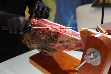 Image showing Sliced dried chamon prosciutto. A man cuts a jamon, a warm toned