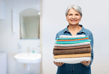 Image showing smiling senior woman with clean bath towels