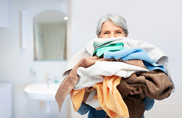 Image showing senior woman with heap of bath towels