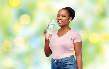 Image showing happy african woman drinks water from glass bottle