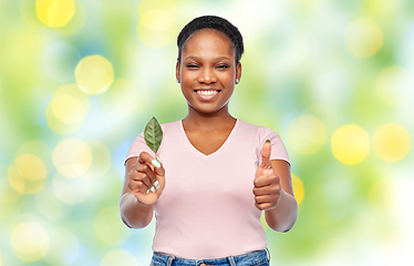 Image showing smiling african american woman holding green leaf