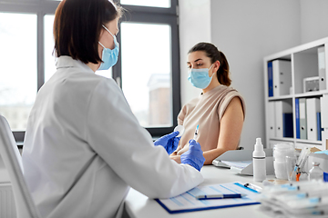 Image showing female doctor with syringe vaccinating patient