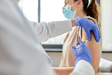 Image showing female doctor with syringe vaccinating patient