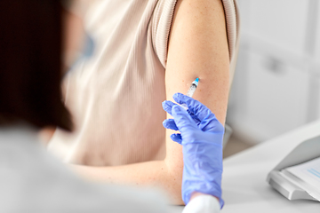 Image showing female doctor with syringe vaccinating patient