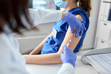 Image showing doctor with syringe vaccinating medical worker