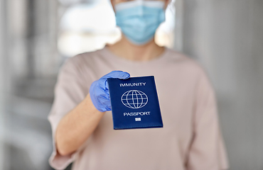 Image showing woman in mask and gloves holding immunity passport