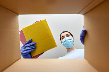 Image showing woman in mask taking cleaning supplies from box