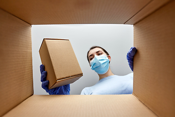 Image showing woman in mask taking box from parcel