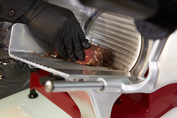 Image showing Man slicing meat with machine