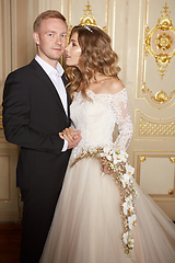 Image showing Wedding couple indoors is hugging each other. Beautiful model girl in white dress. Man in suit. Beauty bride with groom. Female and male portrait. Woman with lace veil. Cute lady and handsome guy