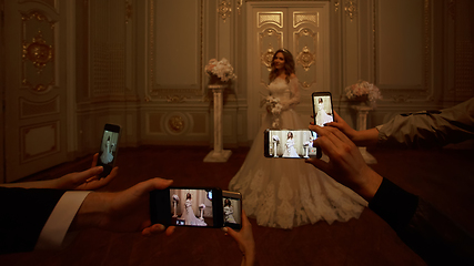 Image showing Guests take photographs of the bride on smartphones. Focus on smartphones.