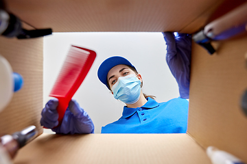 Image showing woman in mask packing parcel box with cosmetics