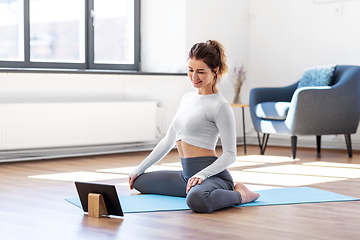 Image showing young woman with tablet pc doing yoga at home